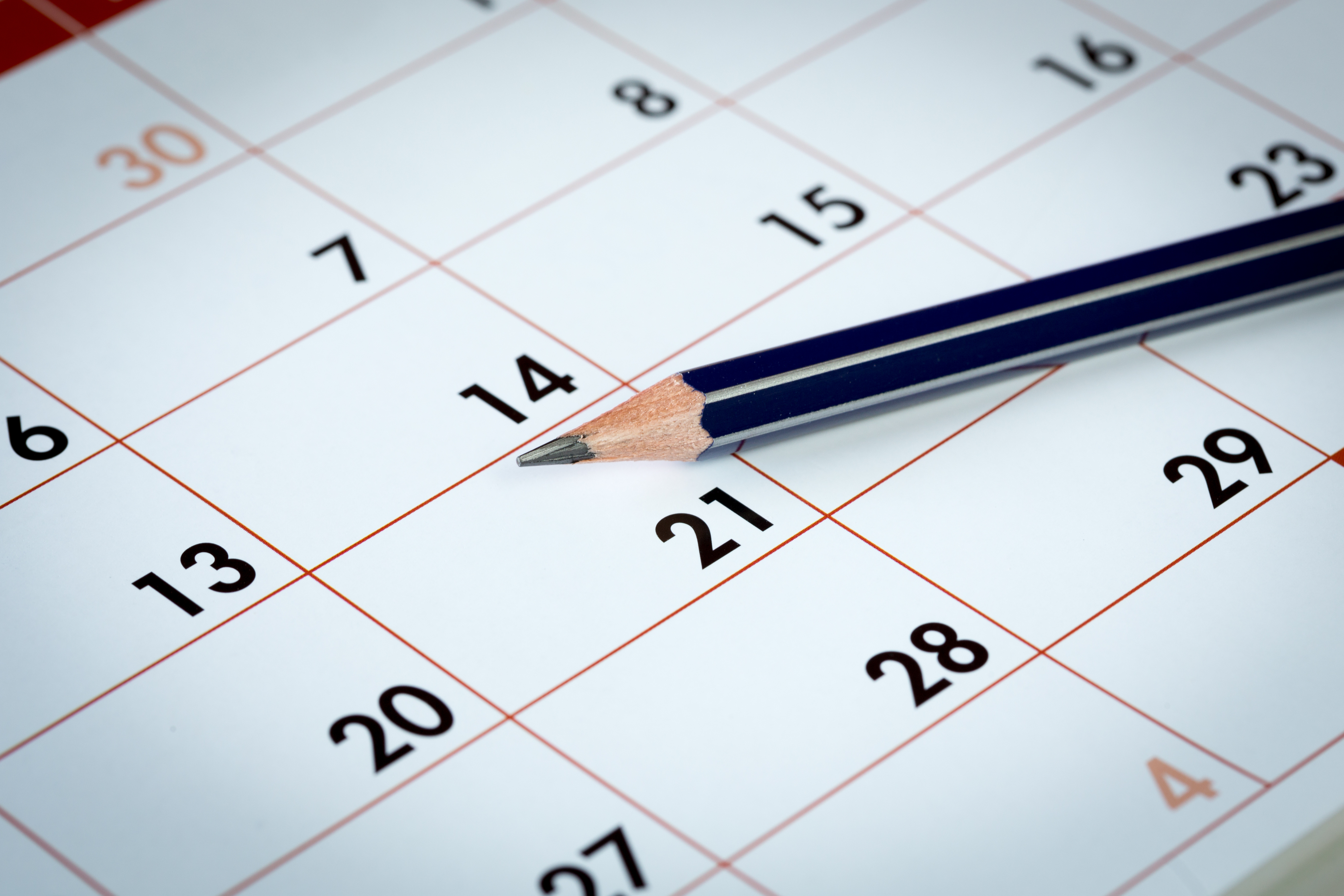 Ein Bleistift liegt auf einer Monatsübersicht eines Kalenders. Die Spitze zeigt auf die Zahl 21.